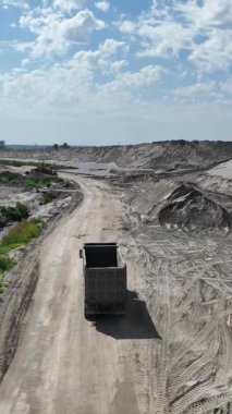 Göl kenarındaki kum ocağına giden bir kamyonun drone görüntüsü.