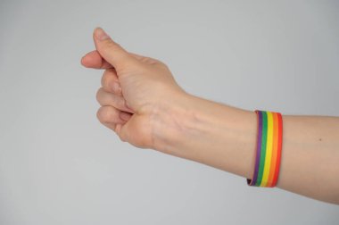 Gökkuşağı bileziği takan kadın parmaklarıyla kalp hareketi yapıyor.