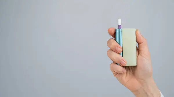 Beyaz arka planda elektronik sigara tutan bir kadın. Tütün ısıtma sistemleri