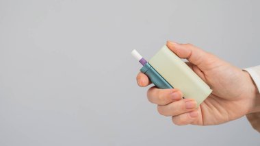 Beyaz arka planda elektronik sigara tutan bir kadın. Tütün ısıtma sistemleri
