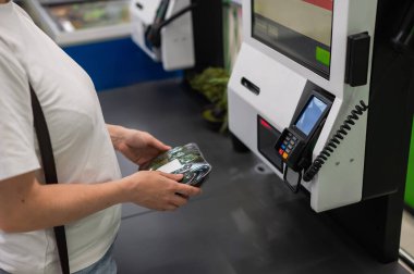 Kadın self servis kasasında salatalık paketini tarıyor.