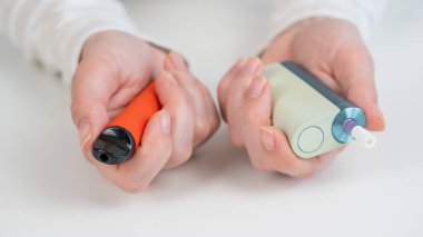 Beyaz arka planda elektronik sigara ve tek kullanımlık tüp tutan bir kadın. Tütün ısıtma sistemleri ve buharlaştırıcı