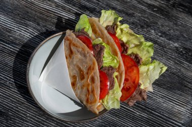 Bir kafedeki masada et ve domatesli ev yapımı düz ekmek.