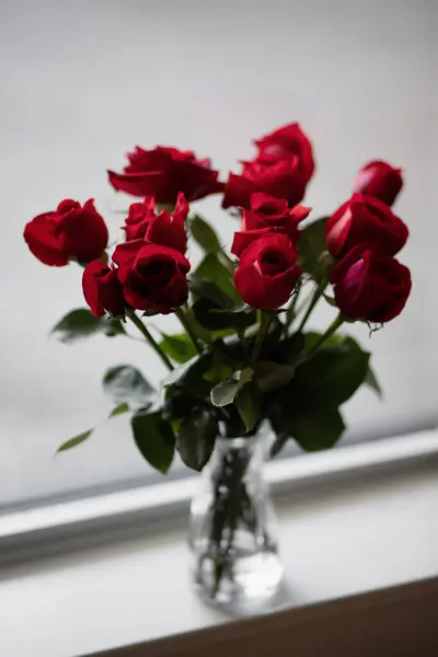 Pencere kenarında bir buket kırmızı gül. Seçici odak.