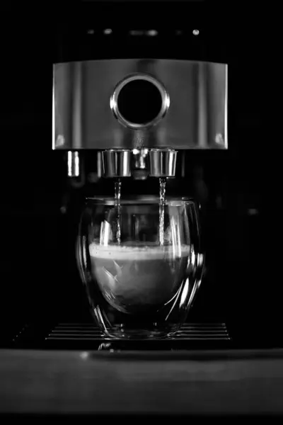 Coffee machine pouring coffee in a glass cup. Black and white.