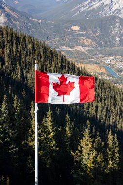 Kanada bayrağı dağların arka planında rüzgarda dalgalanıyor. Banff, Alberta, Kanada.