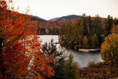 Sonbahar manzarası, renkli ağaçlar, bir göl ve dağlarda bir rıhtım. Mont-Tremblant, Quebec.