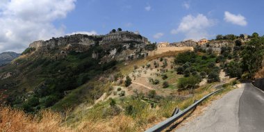 Yol manzarası ve yeşil doğası olan bir tepenin üzerindeki eski İtalyan kasabası.