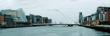 Dublin 'deki Samuel Beckett Köprüsü' nün önü bulutlu bir günde Liffey 'in her iki tarafına da yayılmış.