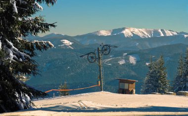 Güneşli bir kış öğleden sonrasında arka planda Yüksek Tatra Dağları (Rozemborog, Slovakya) ile birlikte görülen eski bir kayak kaldırma kulesi)