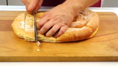Mutfaktaki ahşap kesim tahtasında taze pişmiş altın ekmek dilimleme.