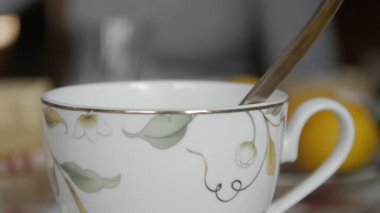 Samimi bir mutfak masasında Arakçı ile doldurulmuş Altın kesimli ve Yaprak Tasarımlı Zarif Tea Kupası