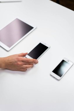 Genç iş kadınının beyaz ekranlı modern akıllı telefonu kullanışının en üst görüntüsü