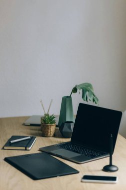 Bilgisayarlı çalışma alanı ve ahşap masadaki akıllı telefon.
