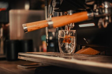 Kahve makinesi ilk espresso damlalarını bardağa dolduruyor.