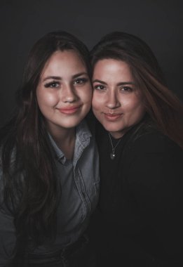 Birbirinin kollarında gülümseyen iki güzel kadın.