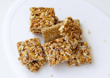 Beyaz arka planda Peanut Chikki ve Til Chikki. fıstıklı chikki ve chikki hindistancevizli tatlı bir yemektir. Hint festivali makar Sankranti özel tatlı.