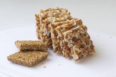 Beyaz arka planda Peanut Chikki ve Til Chikki. fıstıklı chikki ve chikki hindistancevizli tatlı bir yemektir. Hint festivali makar Sankranti özel tatlı.