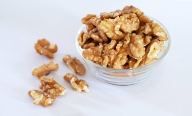 Şeffaf cam kasede ceviz ve bardakta ceviz var. Beyaz arka planda ceviz.