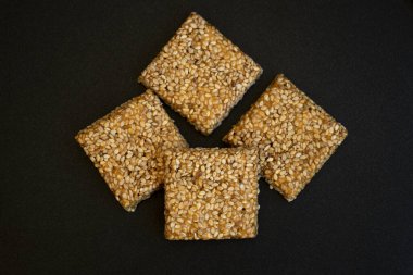 Siyah desenli arka plan üzerine Til Chikki. Til chikki jaggery ve susamlı bir Hint tatlısıdır. Hint festivali makar battı özel tatlı.