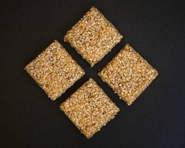 Siyah desenli arka plan üzerine Til Chikki. Til chikki jaggery ve susamlı bir Hint tatlısıdır. Hint festivali makar battı özel tatlı.