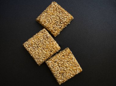 Siyah desenli arka plan üzerine Til Chikki. Til chikki jaggery ve susamlı bir Hint tatlısıdır. Hint festivali makar battı özel tatlı.