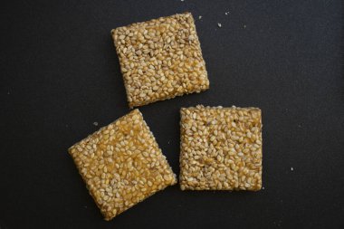 Siyah desenli arka plan üzerine Til Chikki. Til chikki jaggery ve susamlı bir Hint tatlısıdır. Hint festivali makar battı özel tatlı.