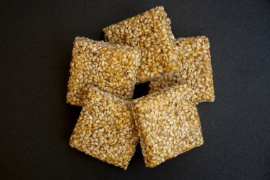 Siyah desenli arka plan üzerine Til Chikki. Til chikki jaggery ve susamlı bir Hint tatlısıdır. Hint festivali makar battı özel tatlı.