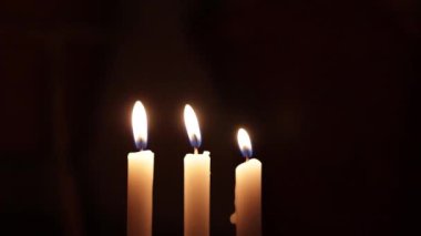 Kibrit çöpü kullanarak üç mum yak. Arka planda üç yanan mum. Üç mum.