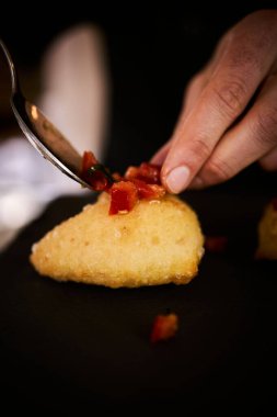 İnce dilimlenmiş taze domates ve kokulu fesleğen yapraklarıyla kaplı çıtır çıtır, altın renginde bir hamur. Bu basit ama lezzetli yemek, çıtır çıtır güveç ile taze Akdeniz lezzetini birleştirir. Aperatif ya da sokak yemeği olarak mükemmeldir..