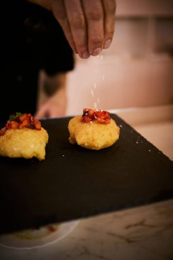 İnce dilimlenmiş taze domates ve kokulu fesleğen yapraklarıyla kaplı çıtır çıtır, altın renginde bir hamur. Bu basit ama lezzetli yemek, çıtır çıtır güveç ile taze Akdeniz lezzetini birleştirir. Aperatif ya da sokak yemeği olarak mükemmeldir..