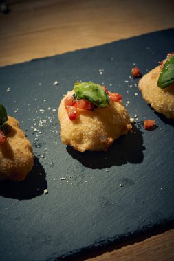 İnce dilimlenmiş taze domates ve kokulu fesleğen yapraklarıyla kaplı çıtır çıtır, altın renginde bir hamur. Bu basit ama lezzetli yemek, çıtır çıtır güveç ile taze Akdeniz lezzetini birleştirir. Aperatif ya da sokak yemeği olarak mükemmeldir..