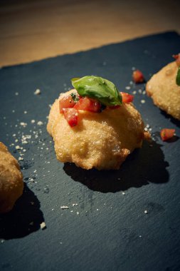 İnce dilimlenmiş taze domates ve kokulu fesleğen yapraklarıyla kaplı çıtır çıtır, altın renginde bir hamur. Bu basit ama lezzetli yemek, çıtır çıtır güveç ile taze Akdeniz lezzetini birleştirir. Aperatif ya da sokak yemeği olarak mükemmeldir..