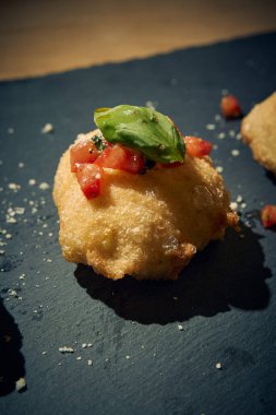 İnce dilimlenmiş taze domates ve kokulu fesleğen yapraklarıyla kaplı çıtır çıtır, altın renginde bir hamur. Bu basit ama lezzetli yemek, çıtır çıtır güveç ile taze Akdeniz lezzetini birleştirir. Aperatif ya da sokak yemeği olarak mükemmeldir..