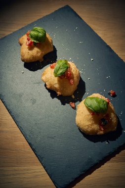 İnce dilimlenmiş taze domates ve kokulu fesleğen yapraklarıyla kaplı çıtır çıtır, altın renginde bir hamur. Bu basit ama lezzetli yemek, çıtır çıtır güveç ile taze Akdeniz lezzetini birleştirir. Aperatif ya da sokak yemeği olarak mükemmeldir..