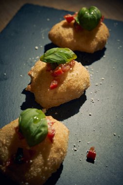 İnce dilimlenmiş taze domates ve kokulu fesleğen yapraklarıyla kaplı çıtır çıtır, altın renginde bir hamur. Bu basit ama lezzetli yemek, çıtır çıtır güveç ile taze Akdeniz lezzetini birleştirir. Aperatif ya da sokak yemeği olarak mükemmeldir..