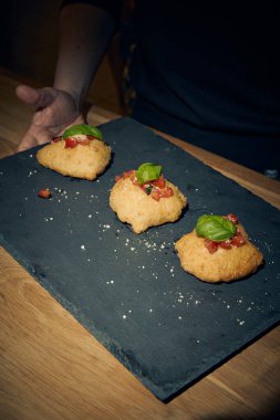 İnce dilimlenmiş taze domates ve kokulu fesleğen yapraklarıyla kaplı çıtır çıtır, altın renginde bir hamur. Bu basit ama lezzetli yemek, çıtır çıtır güveç ile taze Akdeniz lezzetini birleştirir. Aperatif ya da sokak yemeği olarak mükemmeldir..