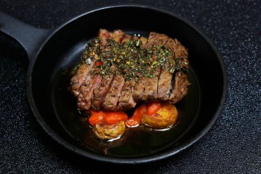 İspanyol chimichurri bifteği patates ve baharatlı brava soslu siyah arka planda.