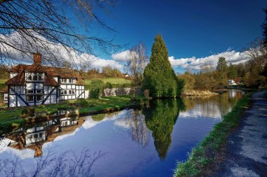 İngiltere 'nin bahçesindeki Loose Valley Kent İngiltere' deki Nr Maidstone. Tudor evinin ve nehirdeki ağaçların yansımaları.