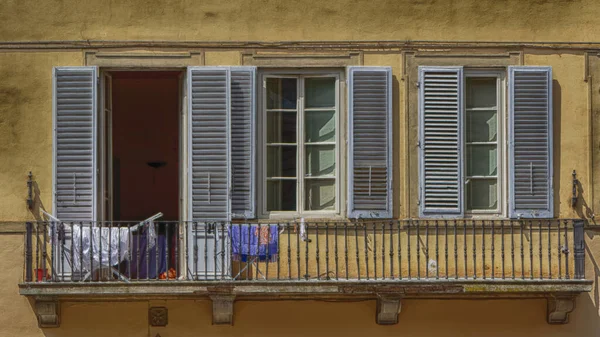 A shuttered window with washing on the balcony in Florence Italy