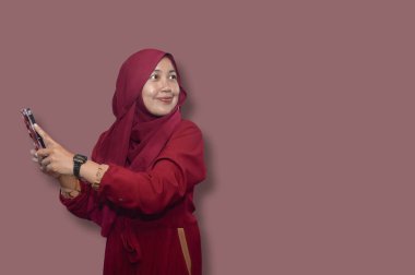 Cep telefonu kullanan genç Asyalı Müslüman kadın portresi.