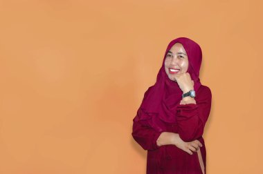 Genç müslüman kadın gülümsüyor ve izole edilmiş pembe kameraya bakıyor.