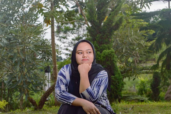 Siyah peçeli bir kadın parkta hayal kurar.