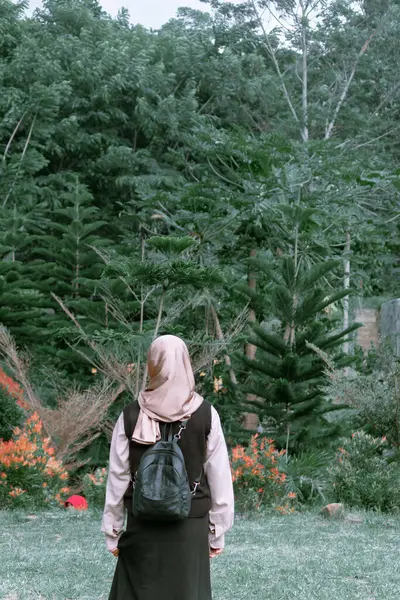 Uzun ağaçlar ve renkli çiçeklerle çevrili yeşil bir ormanda dikilen bir insanın sakin bir görüntüsü..