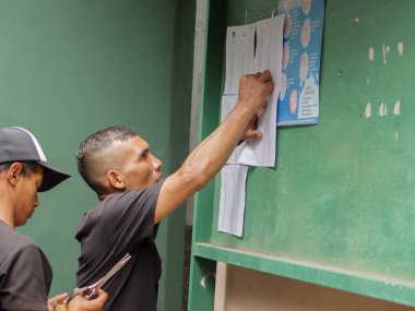 Bandung, Endonezya - 11 Şubat 2024: Endonezyalı bir adam başkanlık seçmen kayıt mektubunu ilan panosuna yapıştırıyor