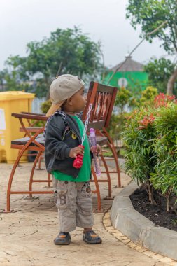 Bandung, Endonezya, 21 Şubat 2024, sıradan kıyafetler ve bahçede çay fincanıyla sabun çalan Asyalı genç.