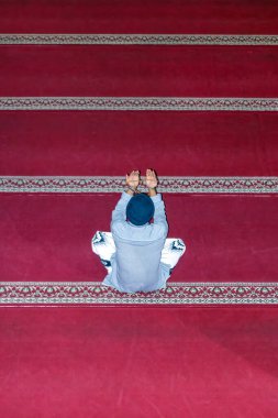 Kendini adamış bir Müslüman camide kırmızı halıda tek başına dua eder.