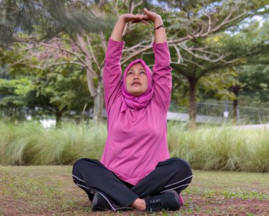 Tesettürlü Müslüman bir kadın yoga yapıyor, rahatlama ve refahı teşvik ediyor.