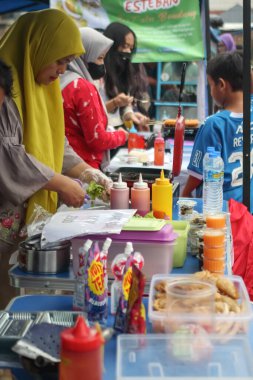 Kalabalık bir markette, Bandung Endonezya 'da yemek hazırlayan satıcılarla dolu canlı bir sokak yemeği tezgahı, 03 Mart 2025