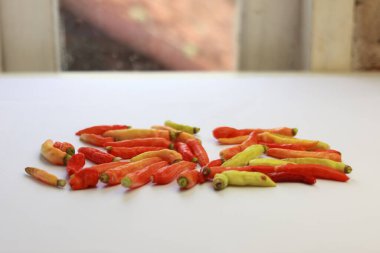 Canlı kırmızı, sarı ve turuncu renklerini gösteren taze kırmızı biberler beyaz arka plana saçılmıştır.